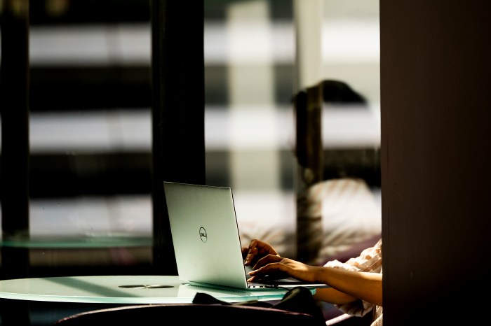 A blurred, dimly lit view of an open laptop on a table inside a modern building interior.