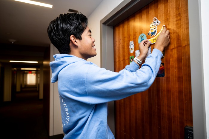A student decorates his dormitory door with colorful stickers and magnets ahead of move-in day.