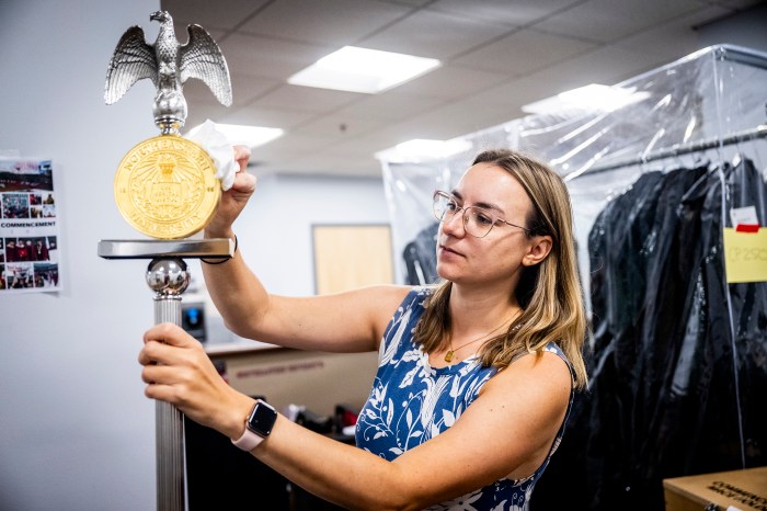 Chelsea Kryspin polishes the ceremonial mace, topped with an eagle and gold medallion, ahead of commencement.