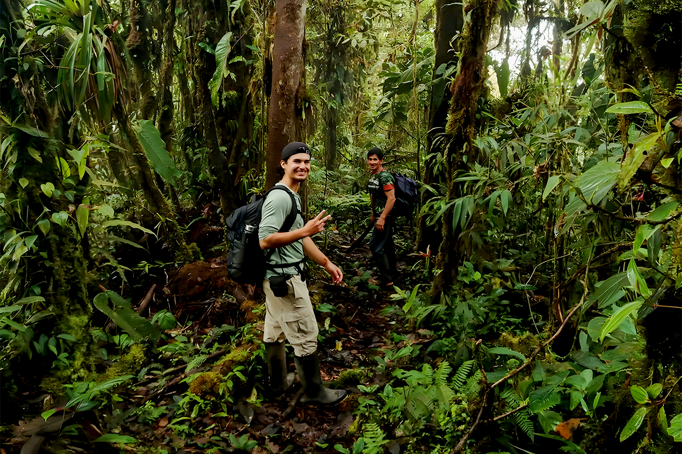 Adrian Baez in hiking gear smiles for a photo while standing in a lush forest.