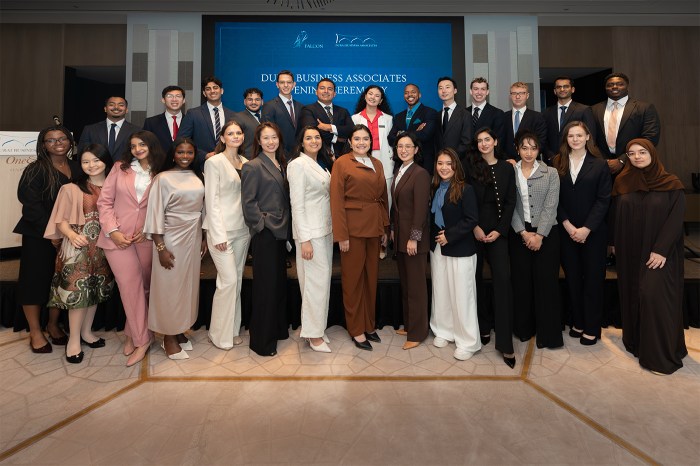 The graduating class of Dubai Business Associates posing together in formal attire on stage.