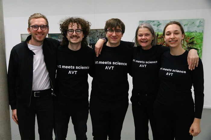 Sierre Ternoey, right, with four colleagues, all wearing matching black "art meets science" shirts, posing together indoors.
