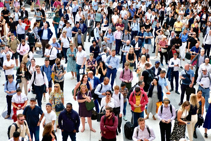 A crowd of diverse people standing on a train platform.