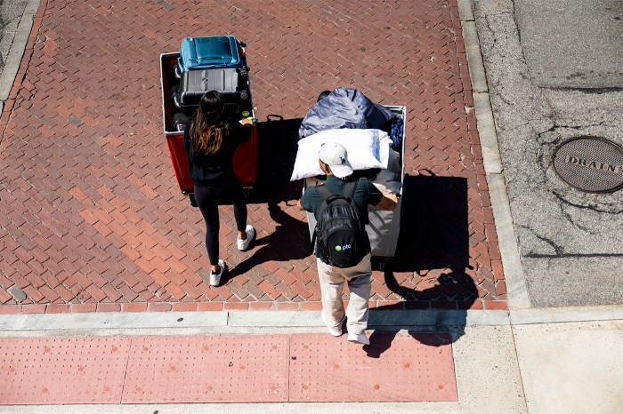 Aerial view of two students pushing luggage carts across a brick courtyard on move-in day.