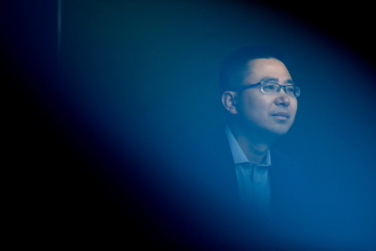 Raymond Fu poses for a portrait with a deep blue background.