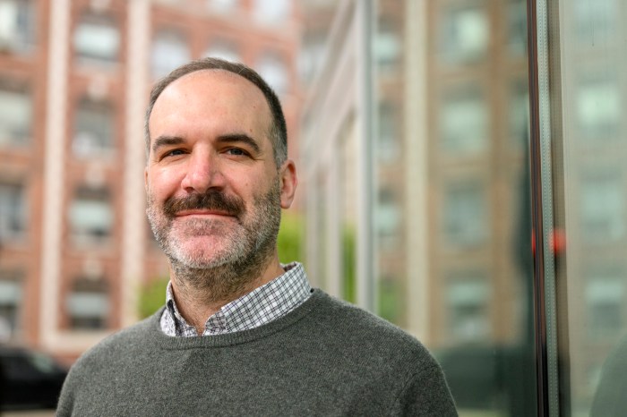 A man with short brown hair and a mustache smiles.