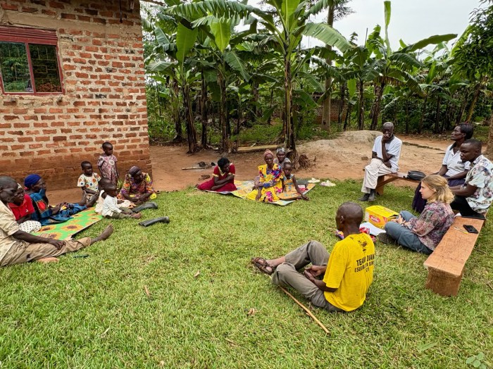 Community members sit together in the grass.