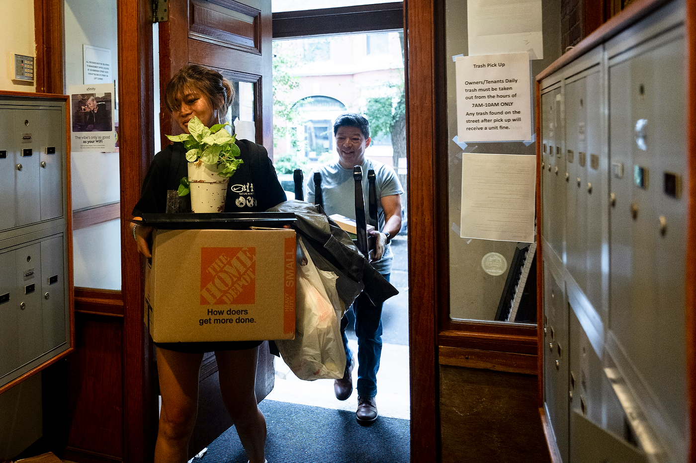Kritika Rai and Tikajit Rai carry boxes through a doorway lined with mailboxes.