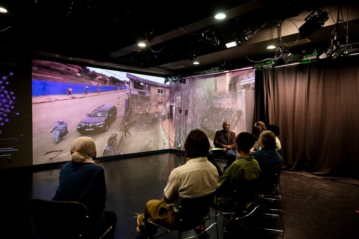 Students viewing an immersive 3D-digitized heritage site displayed across gallery screens.
