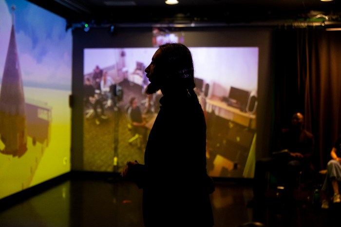 Silhouette of a student in front of a 3D-digitized heritage site displayed on a large screen.