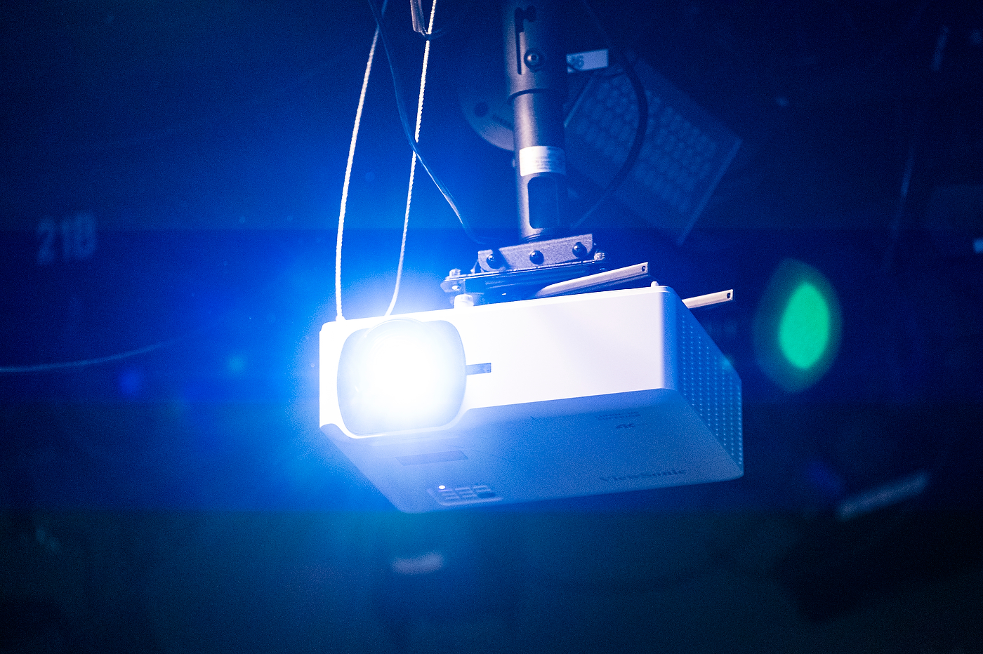 Stage lighting equipment and rigging silhouetted against blue light in a darkened studio.