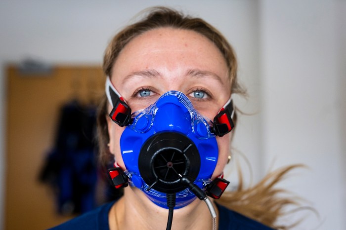 Primer plano de Smith con una máscara respiratoria durante la prueba, mirando directamente a la cámara.