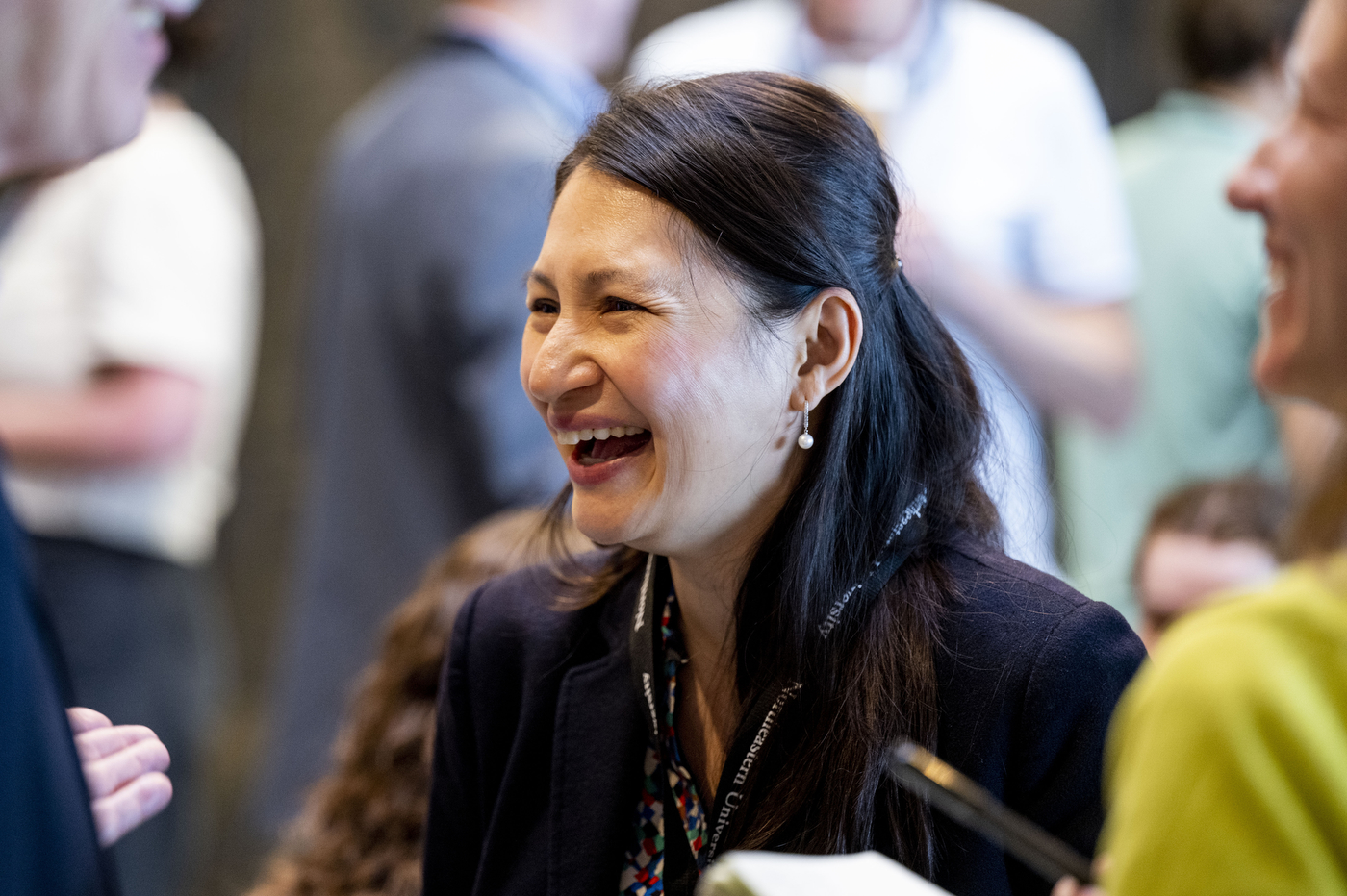 A woman laughing mid-conversation with attendees at the reception.