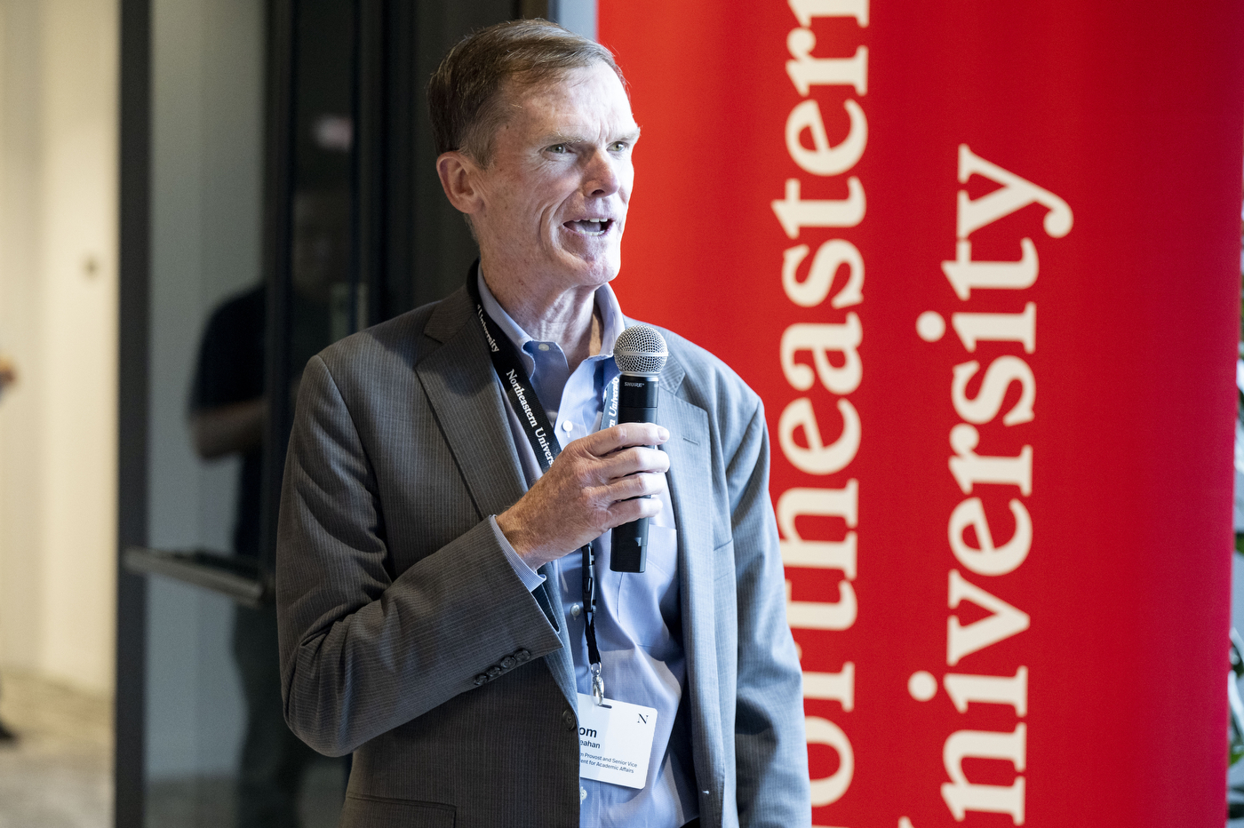 An attendee speaking into a microphone in front of a Northeastern-branded backdrop.