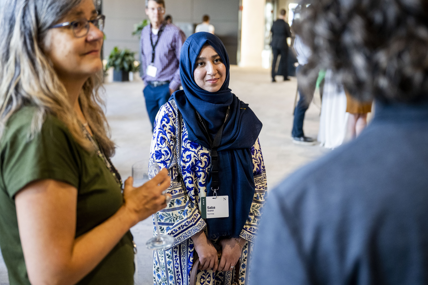 A woman in a hijab smiling in conversation with another attendee at the reception.