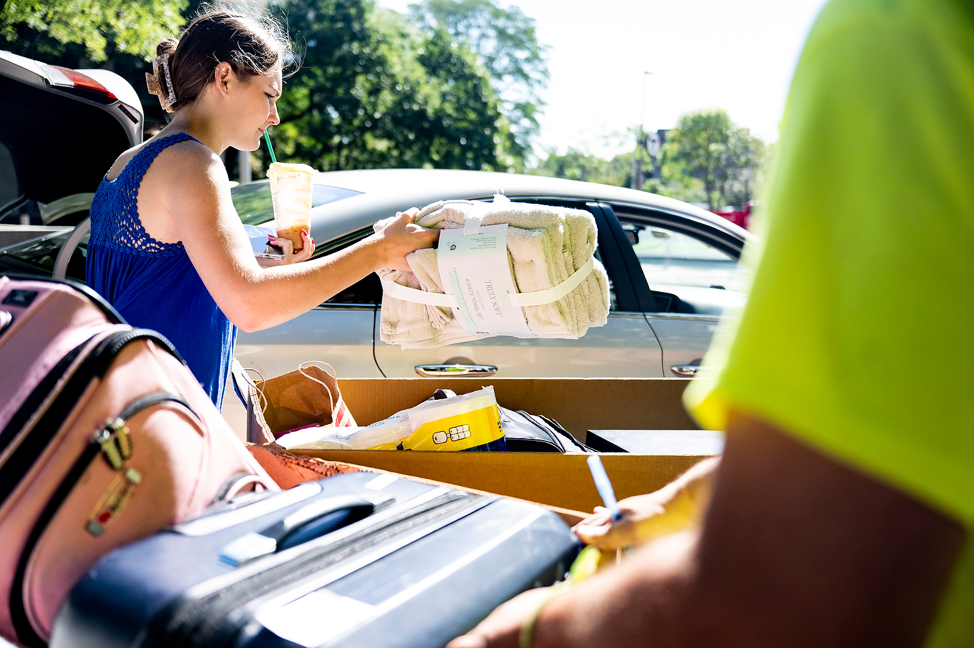Student unloads belongings from car trunk with helper's assistance.