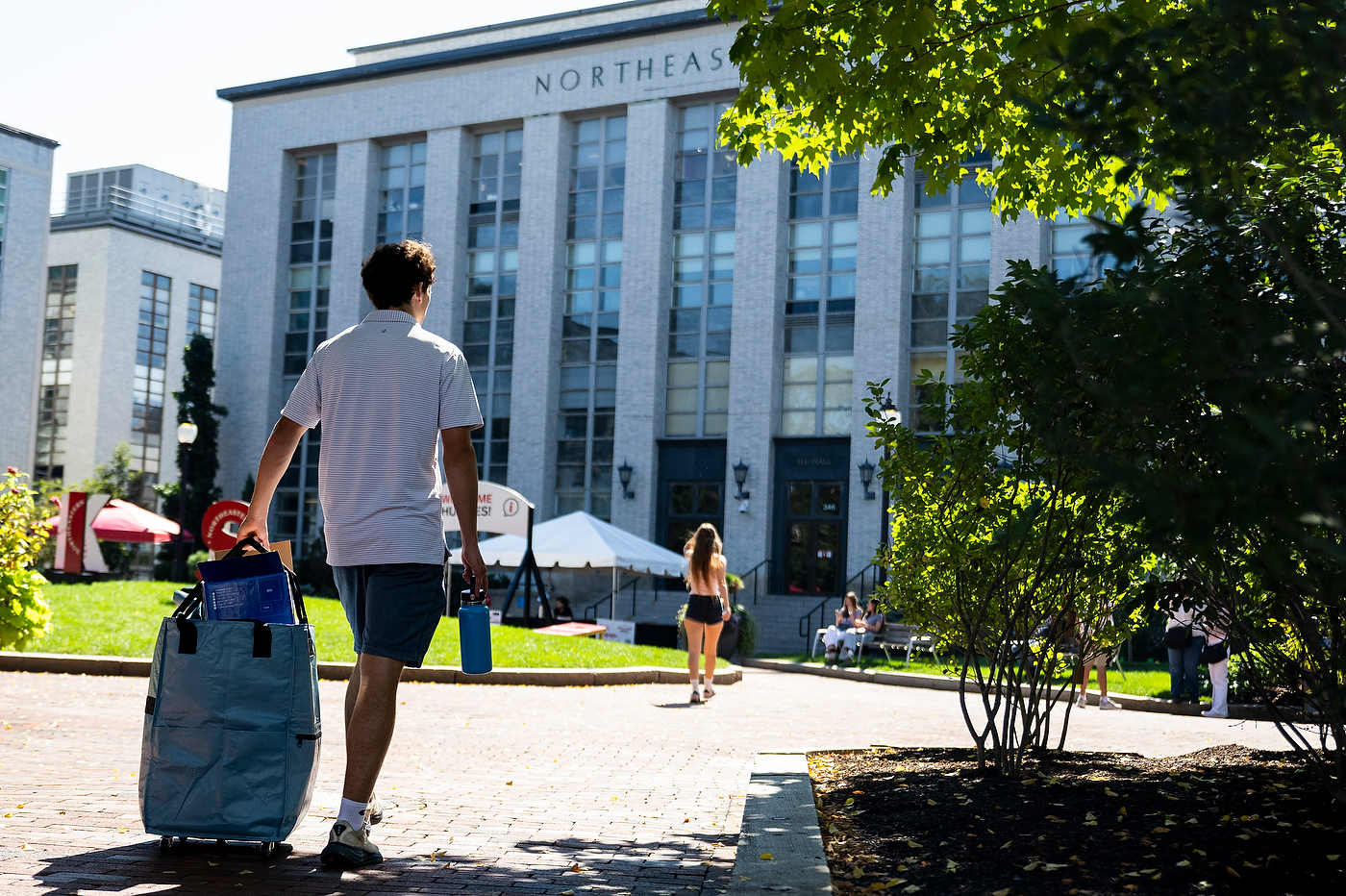 Students walk across a campus quad in front of a university building.
