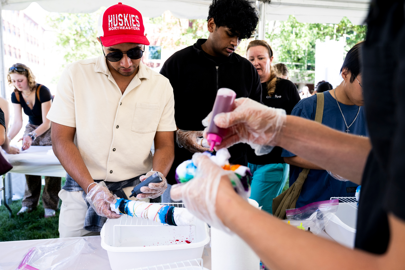 A Northeastern student wearing a red Huskies cap decorates a cookie at the Welcome Week BBQ on Centennial Common.