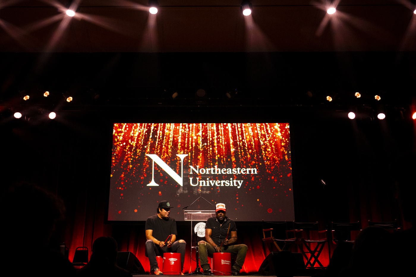 Musicians perform onstage in front of a large Northeastern University screen during the New York City convocation.