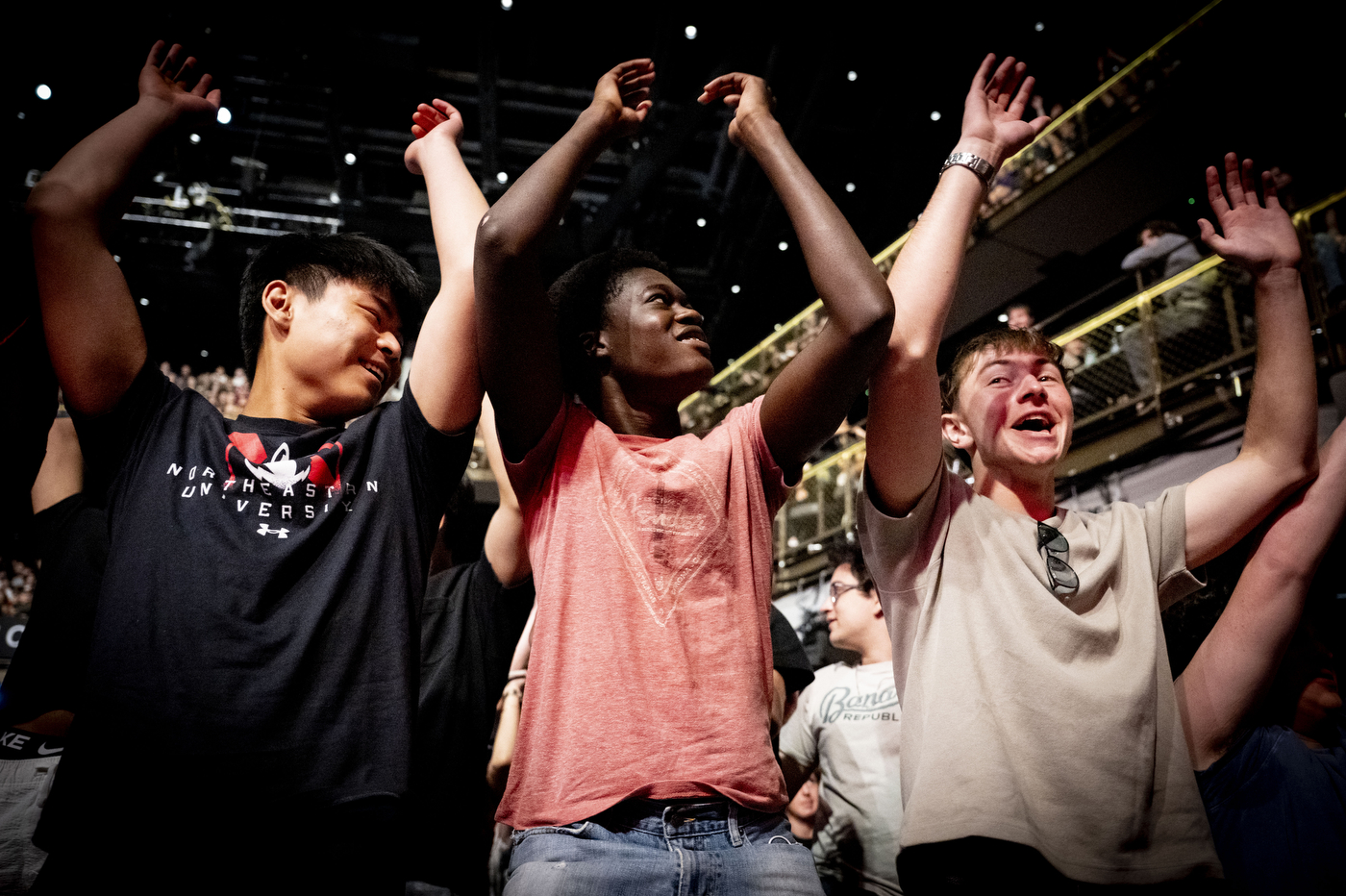 Three students with their arms raised in celebration at the 2026 Convocation ceremony.