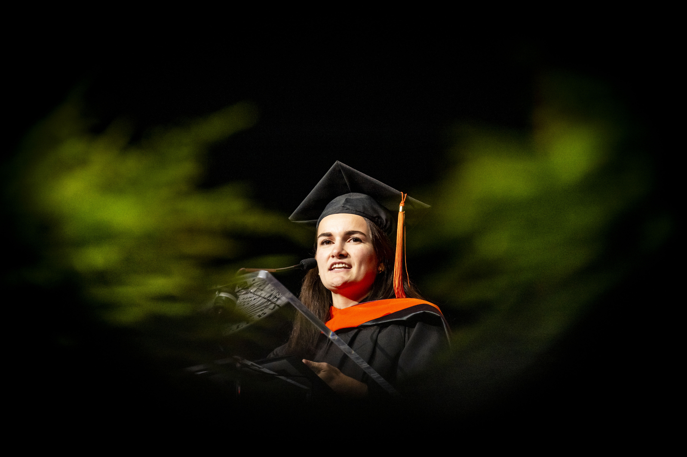 Student silhouette lit in green during the convocation ceremony.