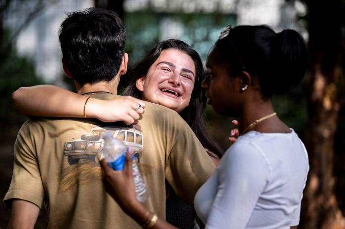 Three students embrace in a group hug, laughing.