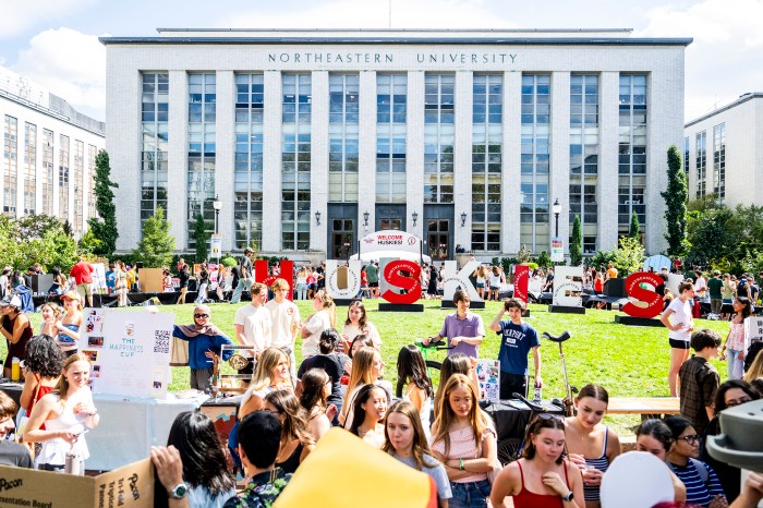 Crowds of students fill the lawn in front of Northeastern's main administration building, with rows of club tables and tents extending into the distance.