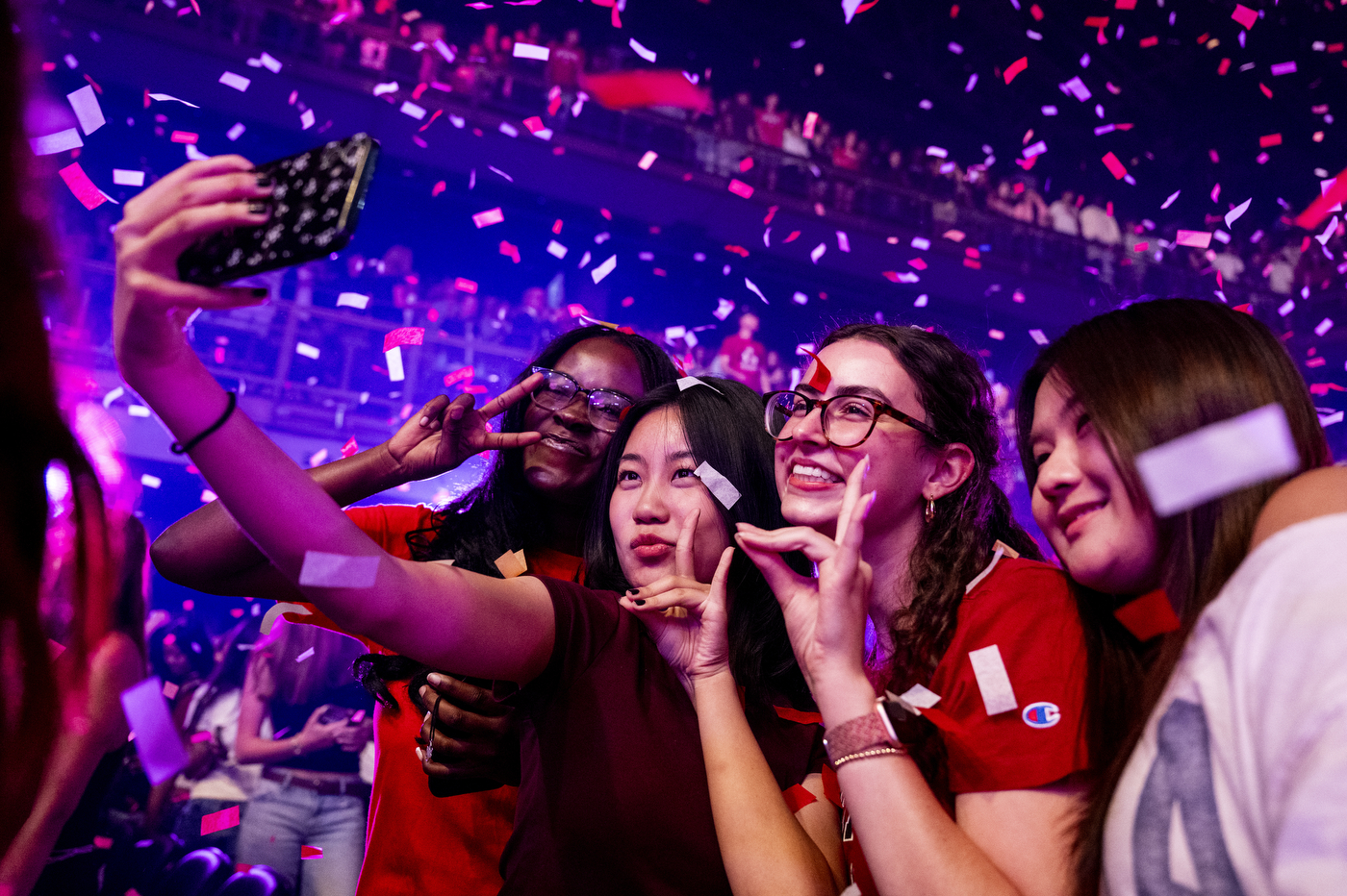 Students take a selfie amid falling confetti, smiling and posing with peace signs.