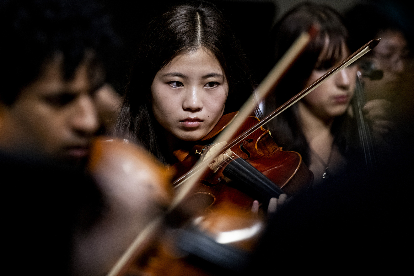 Northeastern University Symphony Orchestra members rehearse with violins.