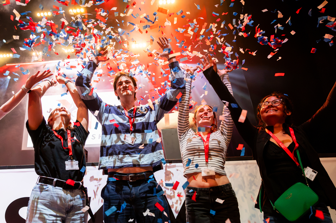 Students put their hands up and cheer among falling confetti.
