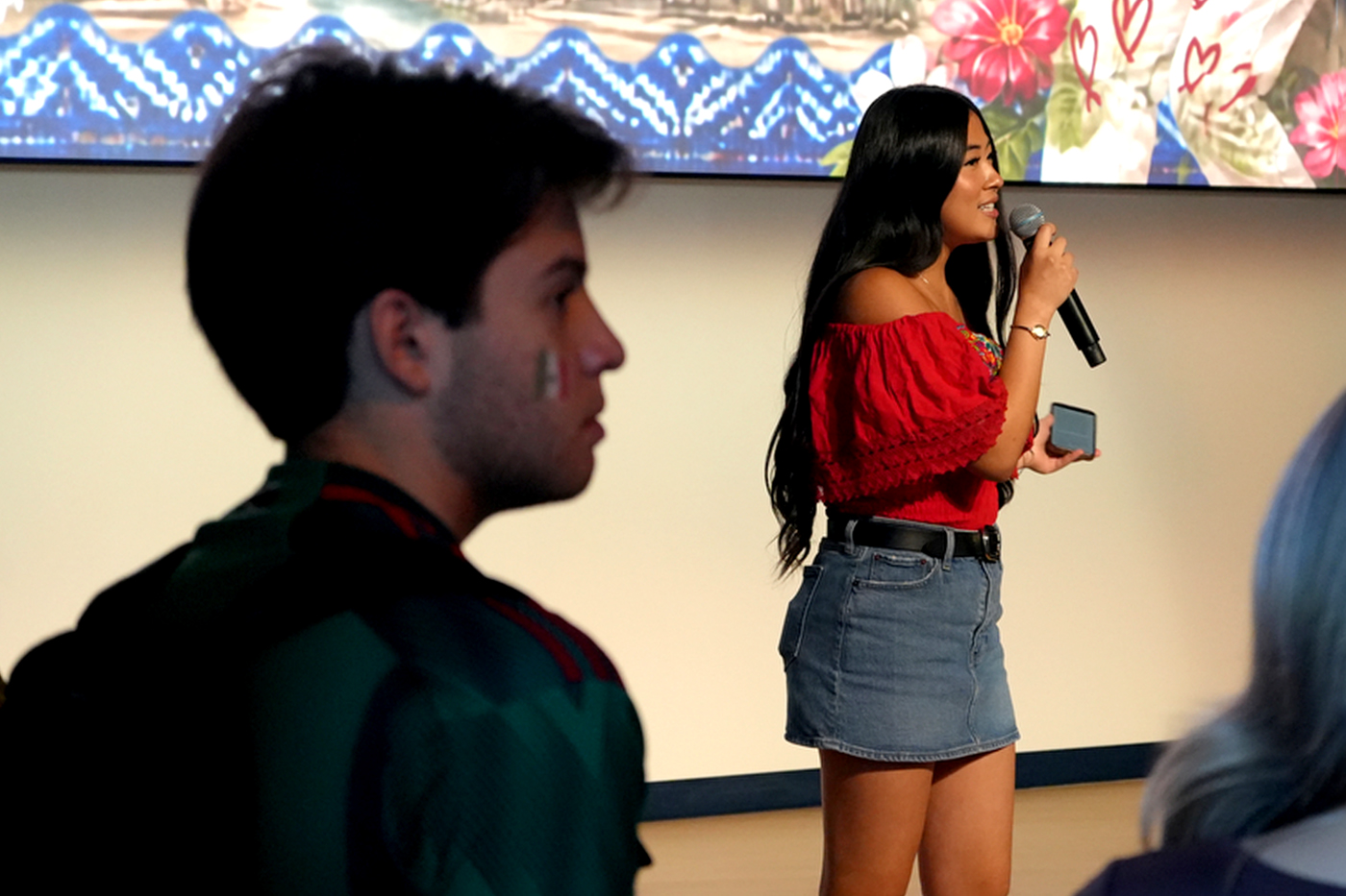 A student speaks into a microphone in front of an audience at the Parade of Flags event.