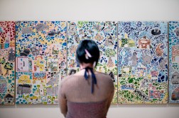 A person looks at a large art piece on a wall.