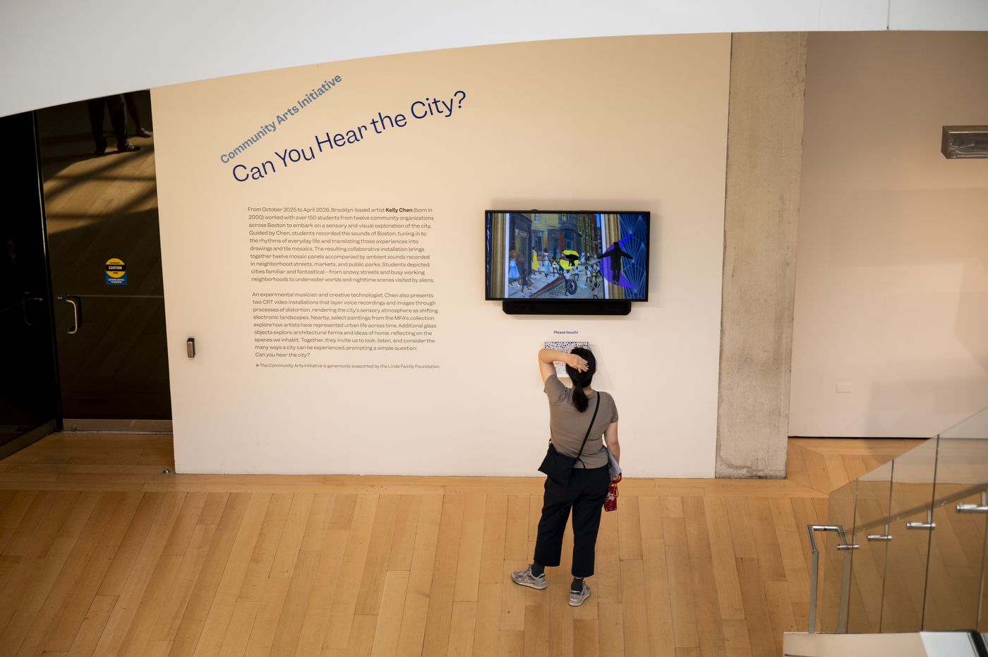 A museumgoer views a video display and wall text for the "Can You Hear the City?" exhibit at the Museum of Fine Arts, Boston.