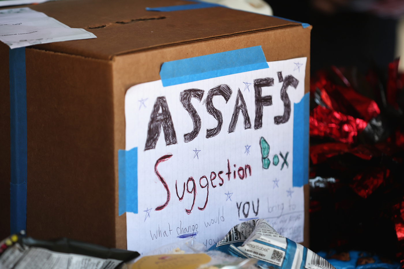 A cardboard box with a sign taped on with "Assaf's suggestion box" written on it.