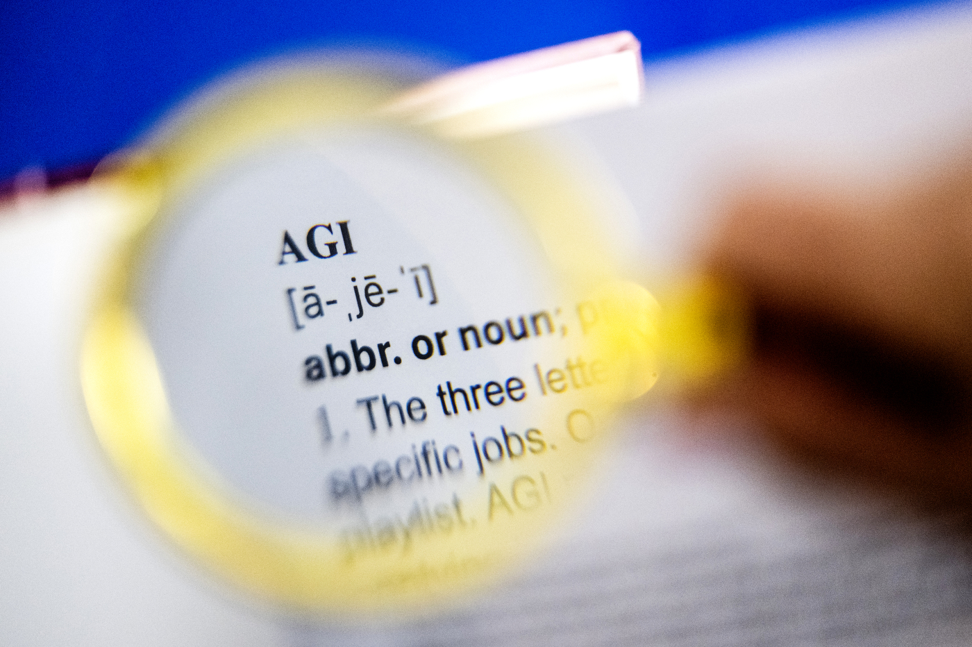 A magnifying glass held over a dictionary entry for "AGI."