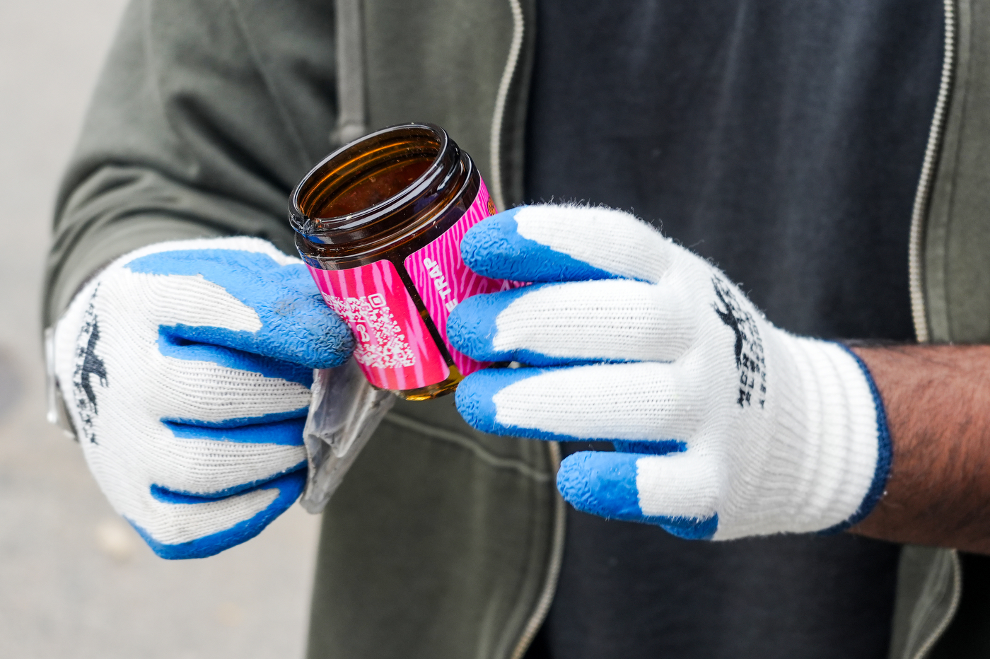 A close up of gloved hands holding an empty product bottle.
