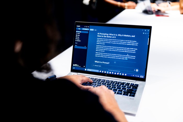 A laptop screen displaying an article titled "AI Prompting: What It Is, Why It Matters, and How to Get Better at It."