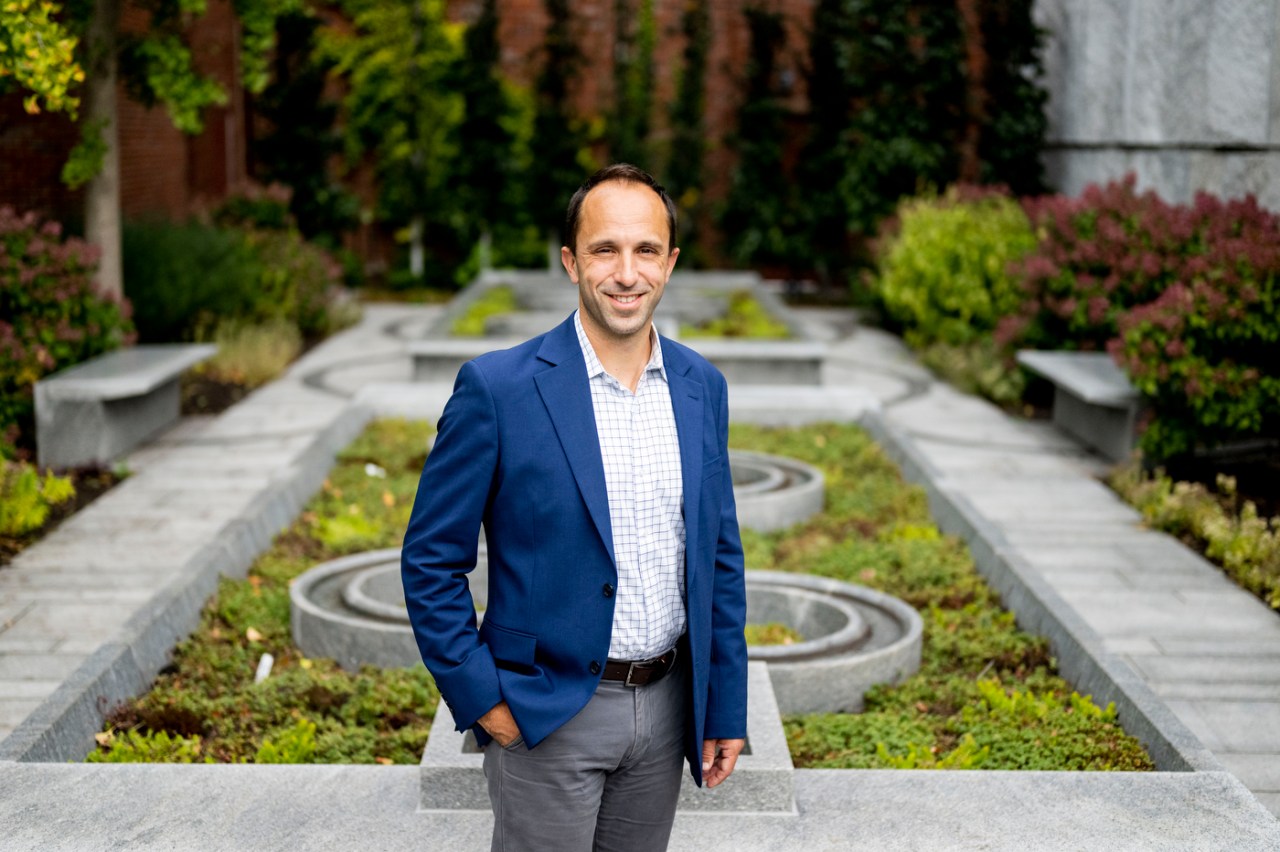 Daniel Draper standing outside at the Peabody Essex Museum in front of a garden with concrete structures in it.